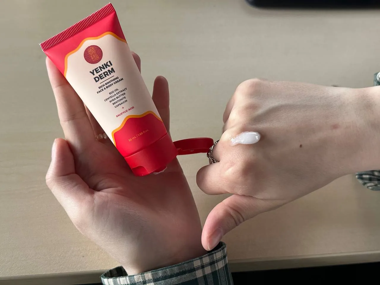 Textura blanca de Yenki Derm en el dorso de la mano junto al tubo abierto